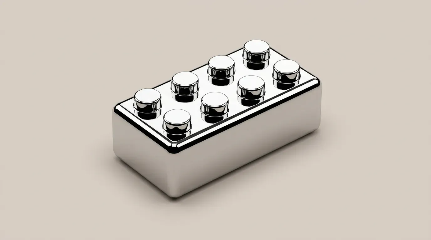 A single polished chrome toy building brick on a plain beige background.