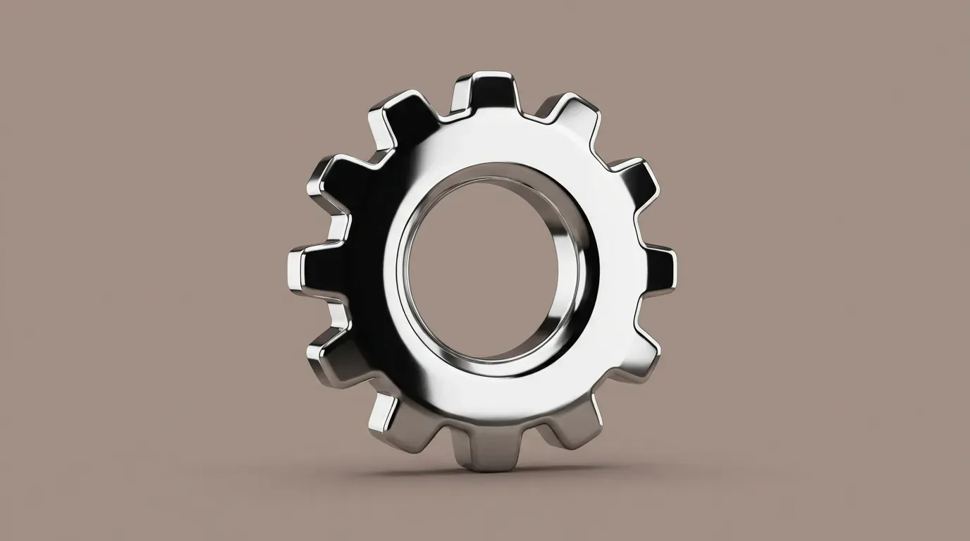 A polished chrome cog standing on end against a plain taupe background.