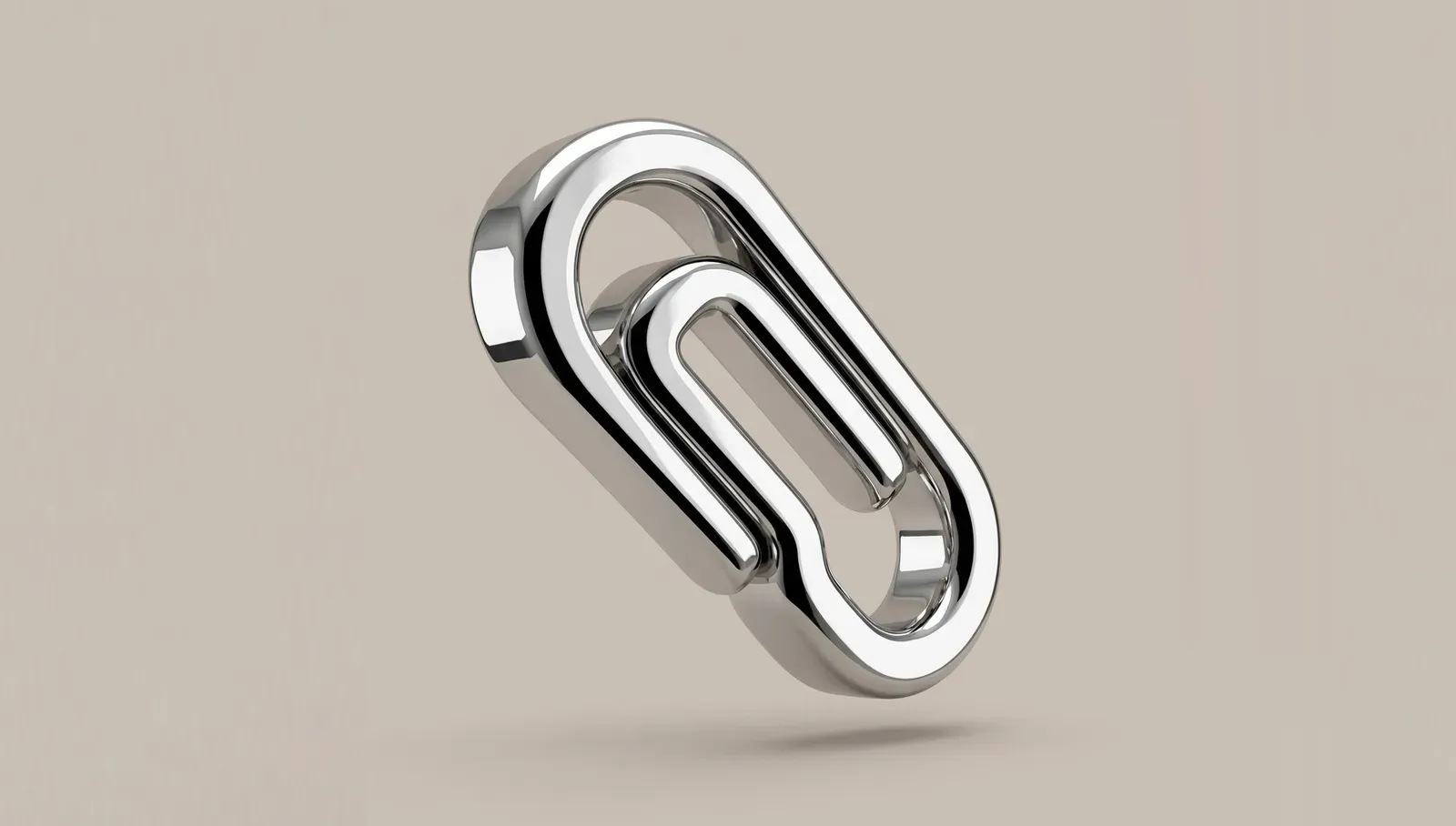 A chrome paperclip standing on end against a pale beige background, one loop clipped through the other.